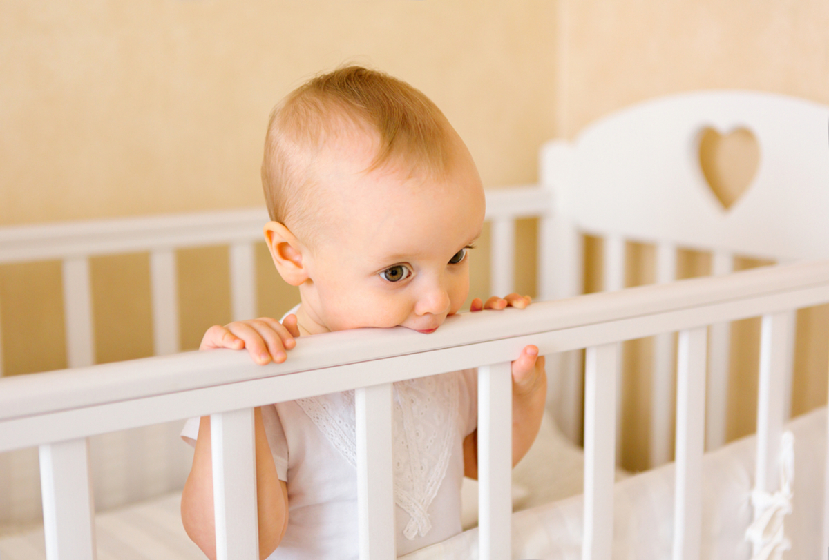 baby chewing on crib
